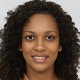 Joyful black young-adult female with long  brown hair and brown eyes