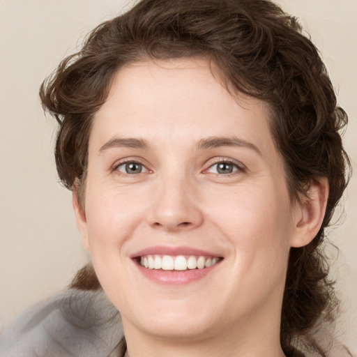 Joyful white young-adult female with medium  brown hair and green eyes