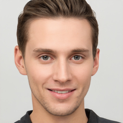 Joyful white young-adult male with short  brown hair and grey eyes