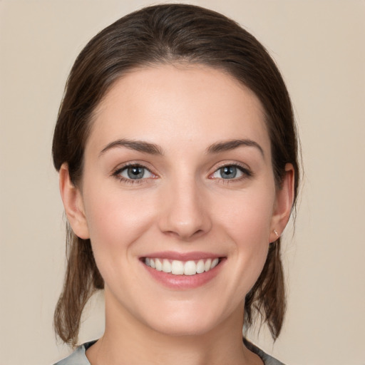 Joyful white young-adult female with medium  brown hair and grey eyes