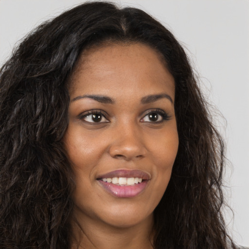 Joyful black young-adult female with long  brown hair and brown eyes