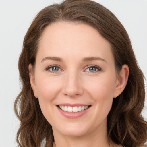 Joyful white young-adult female with long  brown hair and grey eyes