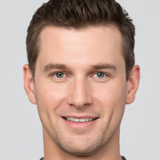 Joyful white young-adult male with short  brown hair and grey eyes