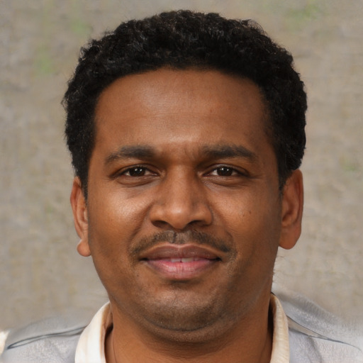 Joyful black young-adult male with short  black hair and brown eyes