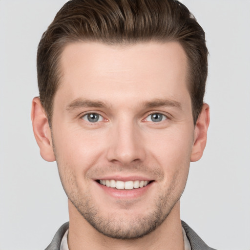 Joyful white young-adult male with short  brown hair and grey eyes