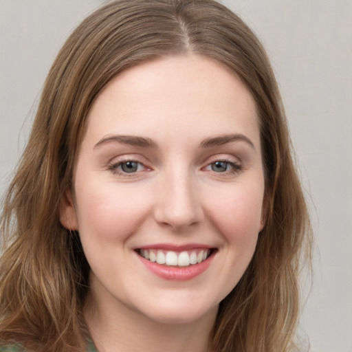 Joyful white young-adult female with long  brown hair and green eyes