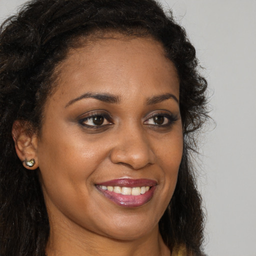 Joyful black young-adult female with long  brown hair and brown eyes