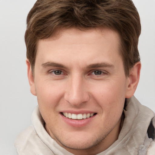 Joyful white young-adult male with short  brown hair and grey eyes