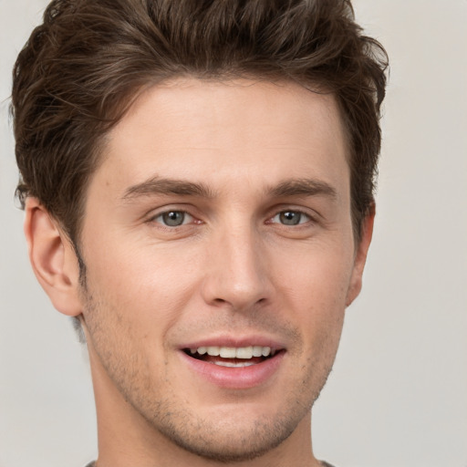 Joyful white young-adult male with short  brown hair and grey eyes