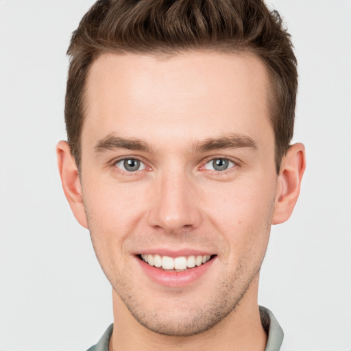 Joyful white young-adult male with short  brown hair and grey eyes