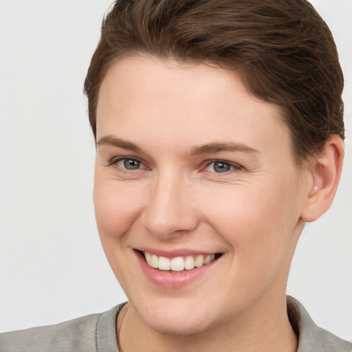 Joyful white young-adult female with short  brown hair and grey eyes