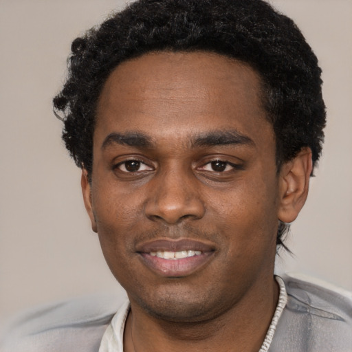 Joyful black young-adult male with short  black hair and brown eyes