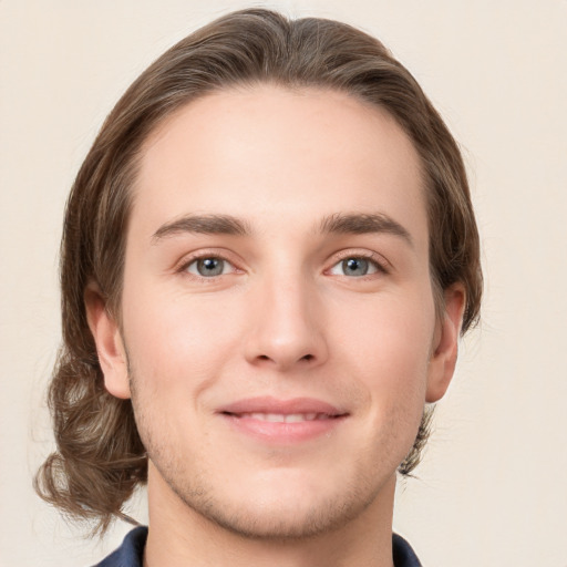 Joyful white young-adult male with medium  brown hair and grey eyes