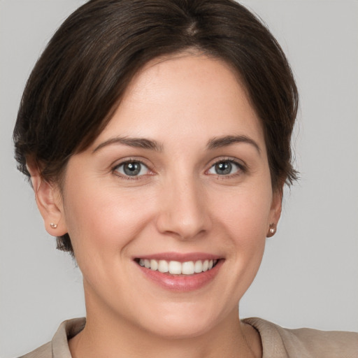 Joyful white young-adult female with medium  brown hair and grey eyes