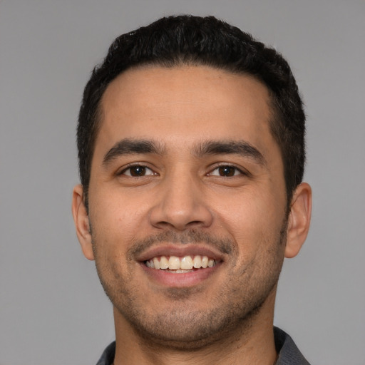 Joyful latino young-adult male with short  black hair and brown eyes