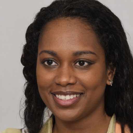 Joyful black young-adult female with long  brown hair and brown eyes