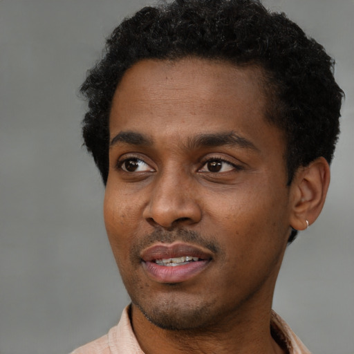Joyful black young-adult male with short  black hair and brown eyes