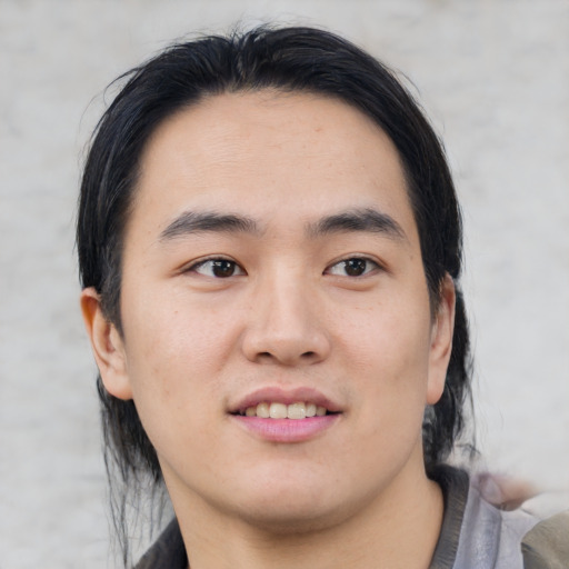 Joyful asian young-adult male with medium  black hair and brown eyes