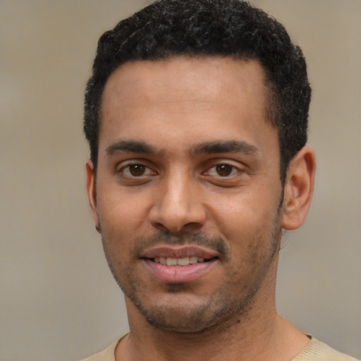 Joyful black young-adult male with short  black hair and brown eyes
