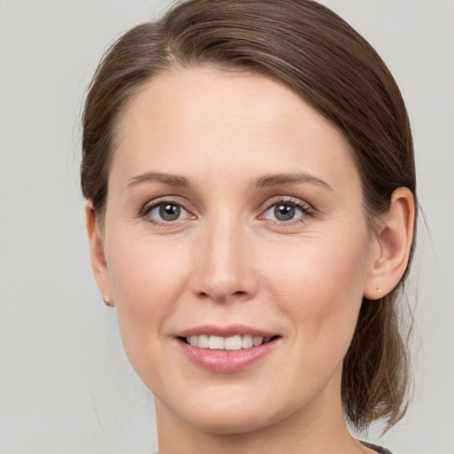 Joyful white young-adult female with medium  brown hair and grey eyes