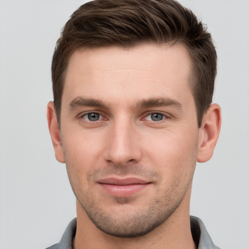 Joyful white young-adult male with short  brown hair and grey eyes