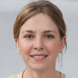 Joyful white young-adult female with medium  brown hair and grey eyes