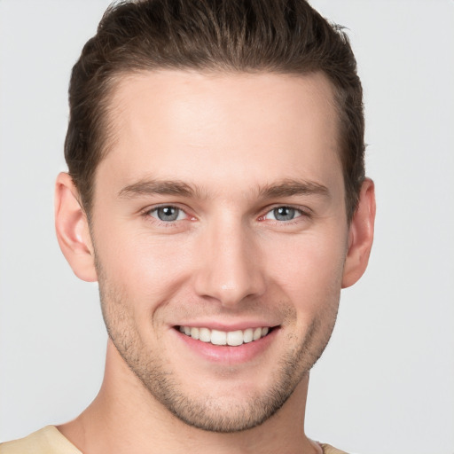 Joyful white young-adult male with short  brown hair and grey eyes