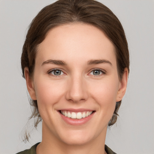 Joyful white young-adult female with medium  brown hair and grey eyes