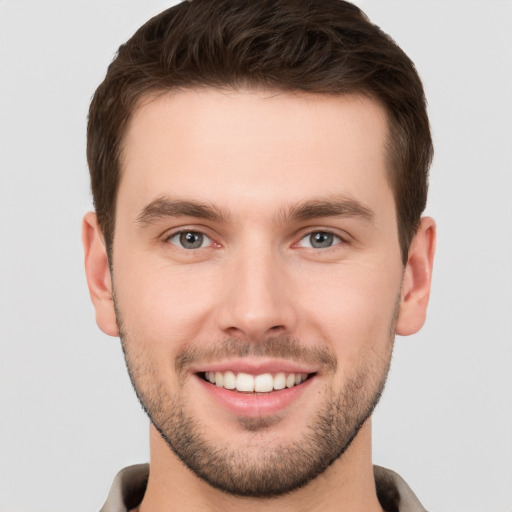 Joyful white young-adult male with short  brown hair and grey eyes