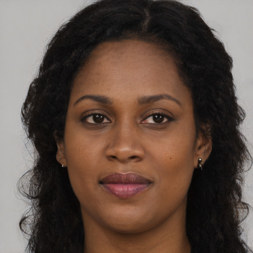 Joyful black young-adult female with long  brown hair and brown eyes