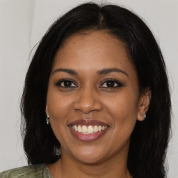 Joyful black young-adult female with long  brown hair and brown eyes