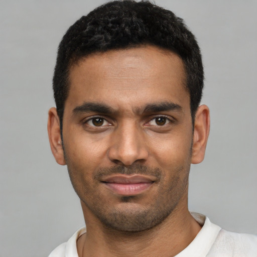 Joyful black young-adult male with short  black hair and brown eyes