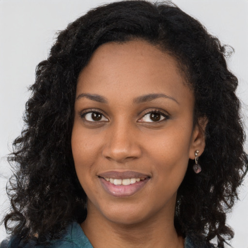 Joyful black young-adult female with long  brown hair and brown eyes