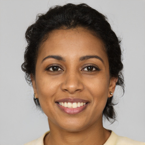 Joyful black young-adult female with long  brown hair and brown eyes