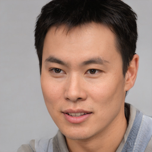 Joyful asian young-adult male with short  brown hair and brown eyes