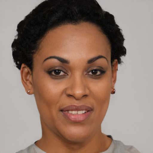 Joyful black young-adult female with short  black hair and brown eyes