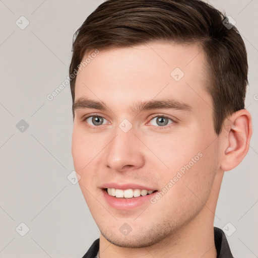 Joyful white young-adult male with short  brown hair and grey eyes