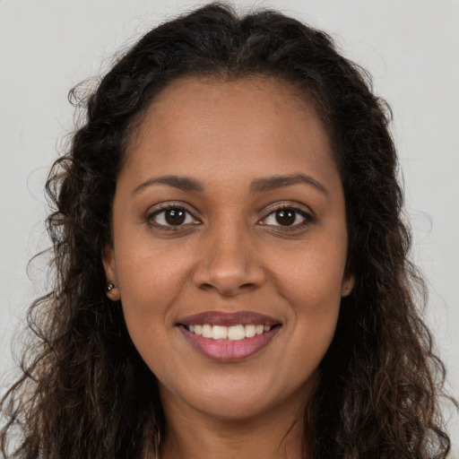 Joyful black young-adult female with long  brown hair and brown eyes