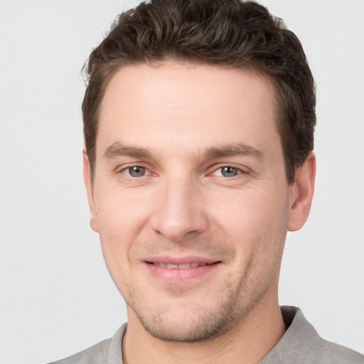 Joyful white young-adult male with short  brown hair and grey eyes