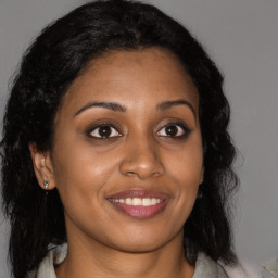 Joyful black young-adult female with long  brown hair and brown eyes