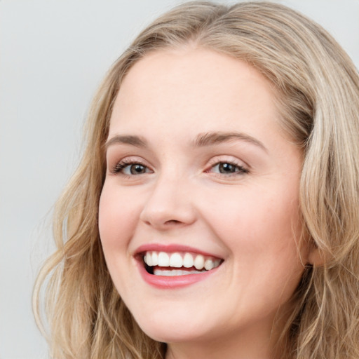 Joyful white young-adult female with long  brown hair and blue eyes