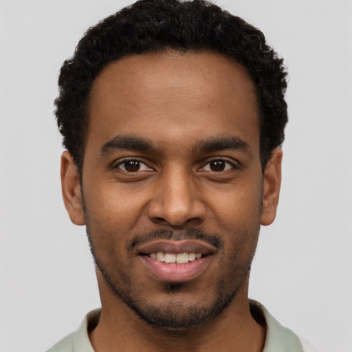 Joyful black young-adult male with short  brown hair and brown eyes