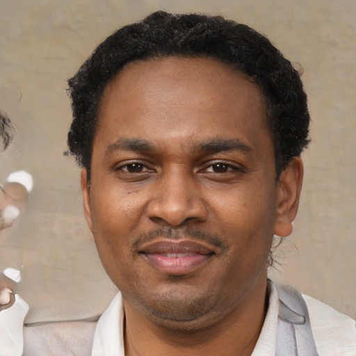 Joyful black adult male with short  black hair and brown eyes