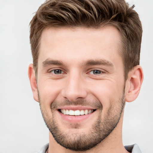 Joyful white young-adult male with short  brown hair and grey eyes