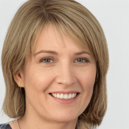 Joyful white adult female with medium  brown hair and green eyes