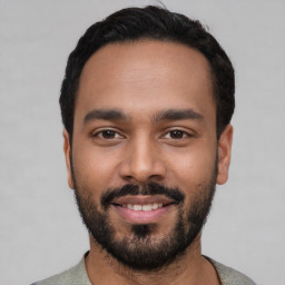 Joyful latino young-adult male with short  black hair and brown eyes