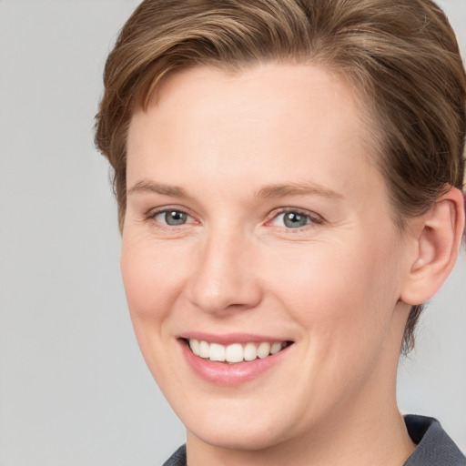 Joyful white young-adult female with short  brown hair and grey eyes