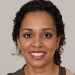 Joyful black adult female with long  brown hair and brown eyes