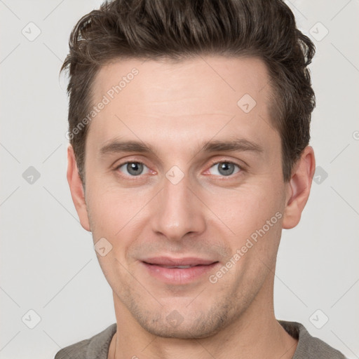 Joyful white young-adult male with short  brown hair and grey eyes