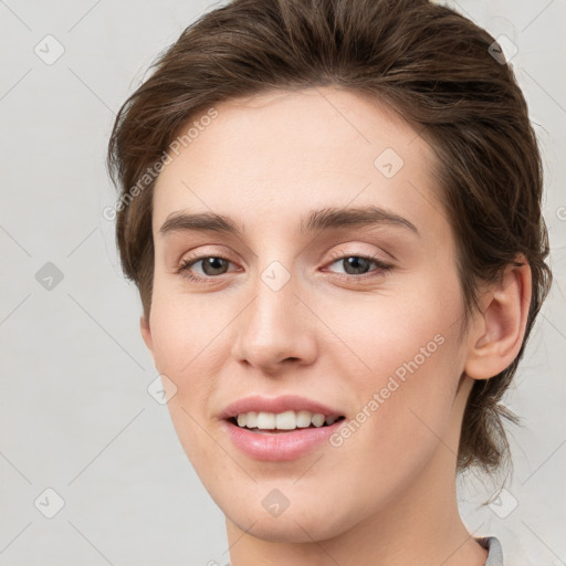 Joyful white young-adult female with medium  brown hair and grey eyes